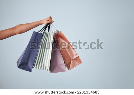 Hands, shopping bags and purchase on studio mockup for fashion, discount or sale against a gray background. Hand of shopper holding bag of gifts, present or luxury retail products on copy space Royalty-Free Stock Photo #2281354683