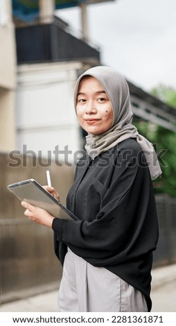 Portrait of young hijab women using tablet in outdoor