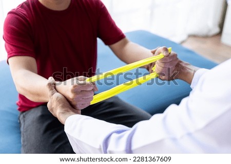 Young Asian man doing physiotherapy and seeking advice from muscle pain with shoulder, limbs in rehabilitation center. Royalty-Free Stock Photo #2281367609