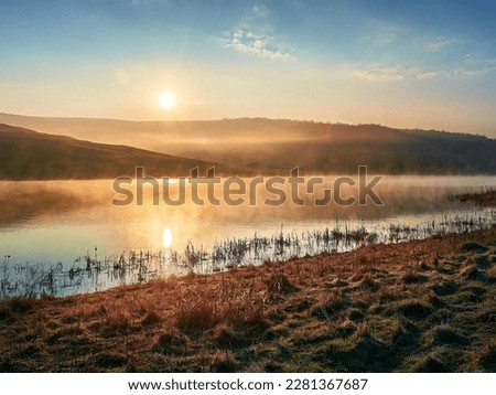 Beautiful lake in golden hour. Mist and fog above the lake. Soft sunlight, golden hour. Nature, climate change, environment. Landscape water reservoir at sunrise. Royalty-Free Stock Photo #2281367687