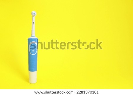 Electric toothbrush on yellow background. copy space for text