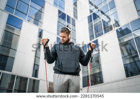 Adult caucasian man training outdoor in the city day Male athlete using rubber elastic resistance band tubes in his daily workout routine Real people health and fitness concept copy space