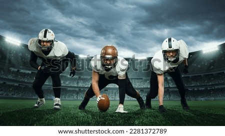 Three sportsmen, american football players in uniform getting ready to play at open air at 3D stadium in evening time. Championship. Concept of sport, competition, action and motion, game, cup. Royalty-Free Stock Photo #2281372789