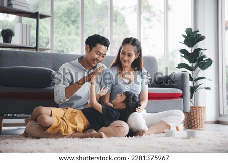 Asian kid cute girl lying on mom and dad happy living relaxing with young mom and dad at home, Happy young family living concept Royalty-Free Stock Photo #2281375967