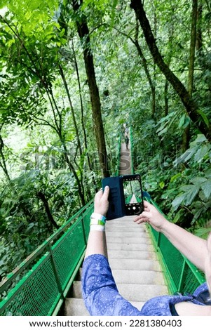 woman take a photo with her handy from stair down in a jungle forest