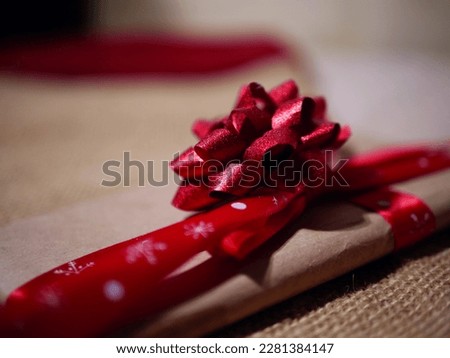 Christmas gift wrapped with a red festive bow decoration close up shot selective focus