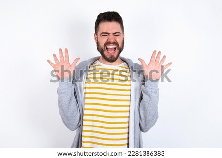 Emotive Young caucasian mán wearing trendy clothes over white background laughs loudly, hears funny joke or story, raises palms with satisfaction,