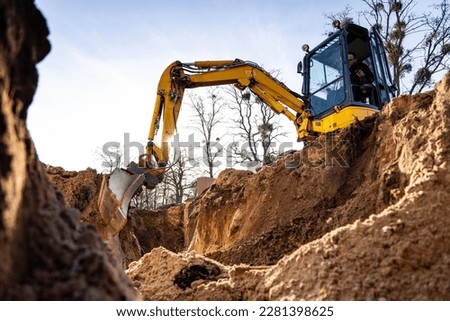 Excavator digging a hole into the ground Royalty-Free Stock Photo #2281398625
