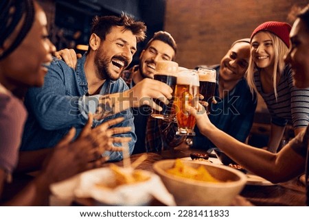 Multiracial group of happy friends having fun while toasting with beer in a bar. Royalty-Free Stock Photo #2281411833