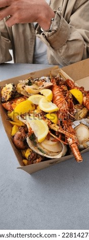 vertical picture of a freshly made seafood platter in sydney fish market, with lobster, shrimp,  oysters, squid, fries chips and lemon 