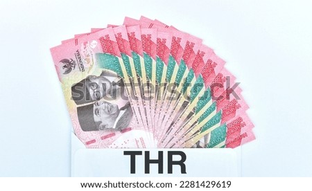 Indonesian Money, rupiah or IDR in envelope with THR Text. The THR envelope contains IDR 100,000 in cash. THR is a holiday allowance on Eid al-Fitr or Eid al-Fitr. best quality white background. Royalty-Free Stock Photo #2281429619