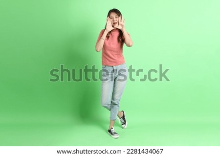 The young adult Asian woman with casual clothes with jeans standing on the green background.