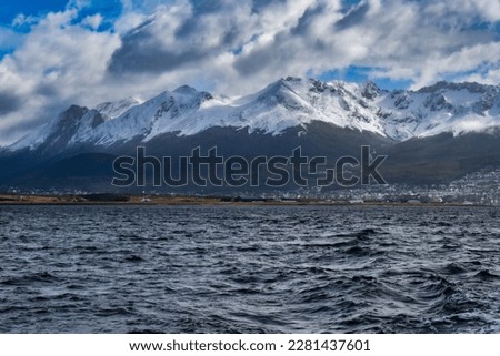 this picture capture on a boat tours to the penguin island in Ushuaia with the amazing view of snow mountains with the town at the bottom of the landscape with blue sky and cold water