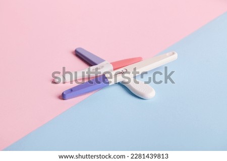 Pregnancy tests on blue and pink bicolor background. Women's health, fertility, planning maternity and pregnancy concept. Stack of test kits with positive results. Copy advertising space Royalty-Free Stock Photo #2281439813