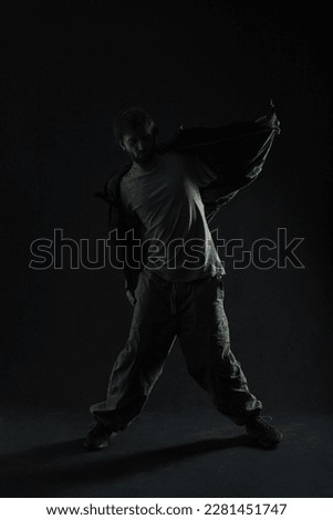 Fashion silhouette of a dancing stylish man in trendy clothes dancing in the dark