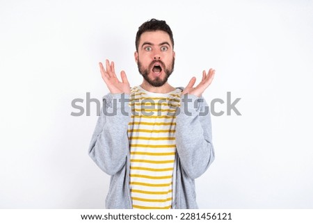 Surprised terrified Young caucasian mán wearing trendy clothes over white background Gestures with uncertainty, stares at camera, puzzled as doesn't know answer on tricky question, People, 