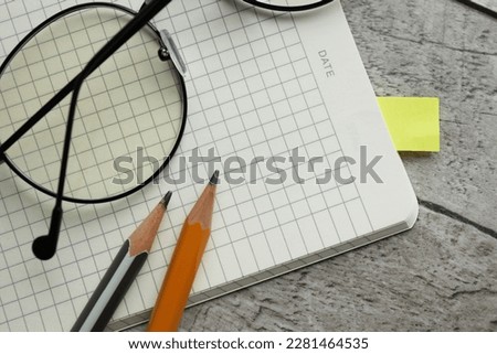 Top view open notepad, pencil and glasses on desktop background