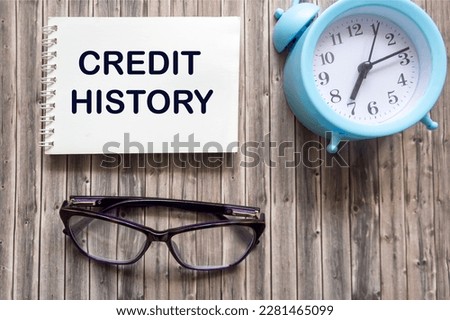 Credit history. text on notepad on wooden background with clock and glasses