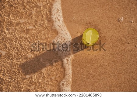 Image of a refreshing lemonade on the sand by the sea. Picture of cocktail among the waves by the sea at the beach. Visual evocative of a summer vacation trip in a tropical location.                  