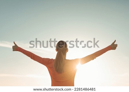 Having a positive mindset, wellbeing and hope concept. Happy young woman standing in a nature sunrise with arms outstretched
