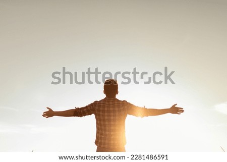 Young man facing sunset rejoices, laughs, smiles looking up to the sky, enjoys life, happiness.	 Royalty-Free Stock Photo #2281486591