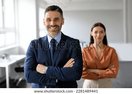 Portrait of two business leaders partners posing with folded arms and smiling at camera, working together in office interior, selective focus on businessman Royalty-Free Stock Photo #2281489441