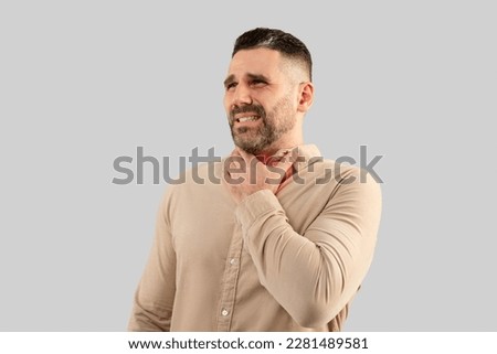 Throat pain. Portrait of ill businessman touching his neck, suffering sore throat, viral infection or flu symptoms, posing on light grey studio background Royalty-Free Stock Photo #2281489581