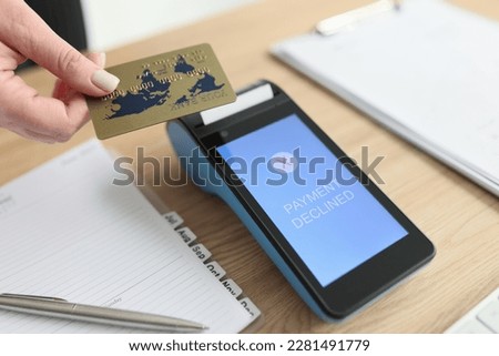 Woman puts credit card to terminal trying to pay for services online. Payment declined due to technical error. Device on wooden table in office closeup