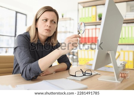 Suspecting woman with magnifying glass seeks information on internet in office closeup. Fact checking to find trustful online sources Royalty-Free Stock Photo #2281491785