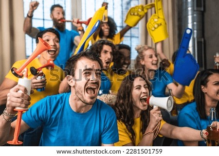 Multiracial joyful sport fans watching game on TV at home - Supporters having fun on sofa for competition event on TV - Friends celebrating victory when sport team wins worlds championship