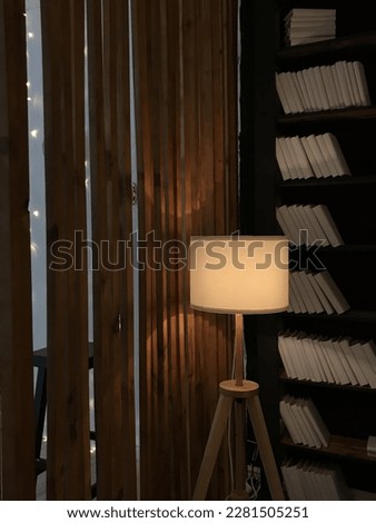 A tall lamp in a library where there is no one
