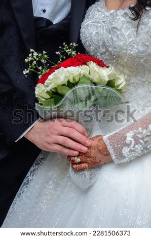 An Arab bride and groom holding a bouquet of flowers with henna tattoos on the bride's hand Royalty-Free Stock Photo #2281506373