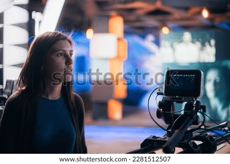 A young female director of photography at work behind a movie camera on a film set for a movie, commercial or broadcast. Modern photography technology.