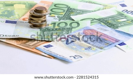 Euro coins stacked on each other in different positions over euro banknotes with a white background with space for text