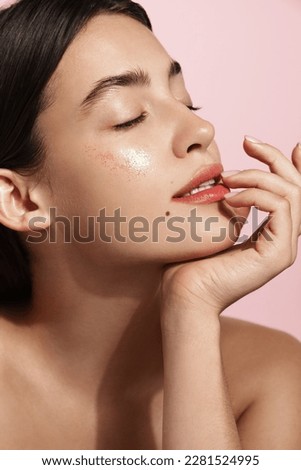 Beauty and women healthcare. Vertical portrait of beautiful woman, has glowing clear, natural skin without blemishes, close eyes, looks relaxed after skincare routine, pink background.