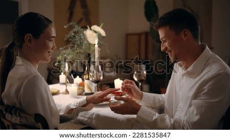 Happy guy wearing engagement ring at evening room. Loving woman saying yes at romantic dinner atmosphere. Enamoured couple touching foreheads bonding at night place. Celebrating marriage proposal Royalty-Free Stock Photo #2281535847