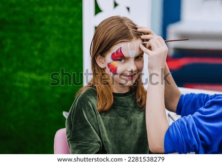 A professional make-up artist, artist woman paints on her face with paints face painting, drawing, children's makeup for a little beautiful girl, child. Photography, art, concept, lifestyle. Royalty-Free Stock Photo #2281538279