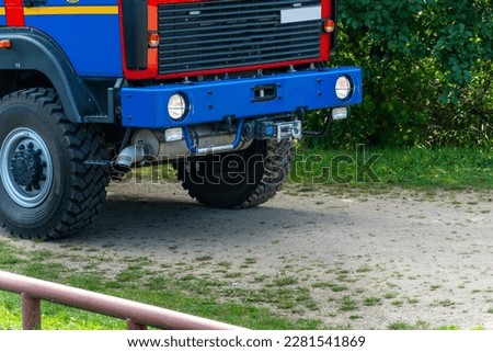A red fire truck stands on a dirt road in nature. A fire in the forest. Exercises of the fire brigade on fire prevention in the forest and the private sector.