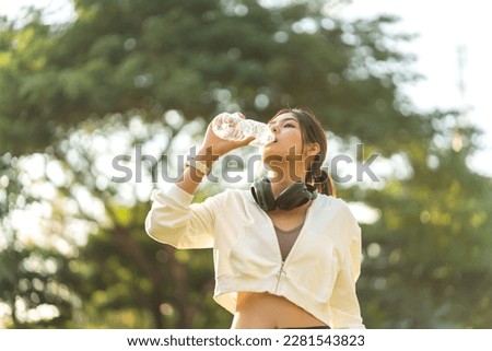 Portrait sport asian beauty body slim woman drinking water from a bottle while relax and feeling fresh,  refresh drink,  wellness, healthcare, mineral at green park.Healthy liquid lifestyle concept Royalty-Free Stock Photo #2281543823