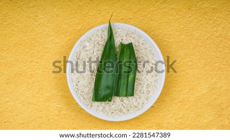 Uncooked Indonesia rice in white bowl over yellow background