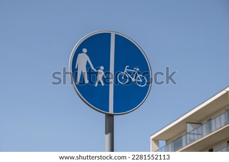 Cyclist and pedestrian route sharing sign. Road sign Pedestrian and bicycle can cross the street here on the background of blue sky 