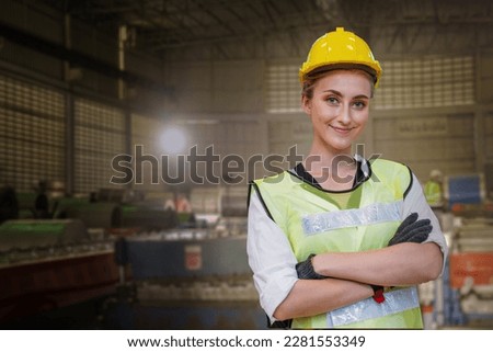 Portrait of manual woman worker is standing with confident with working suite dress and safety helmet in front machine for heavy industry factory. Steel metal sheet plant for production.