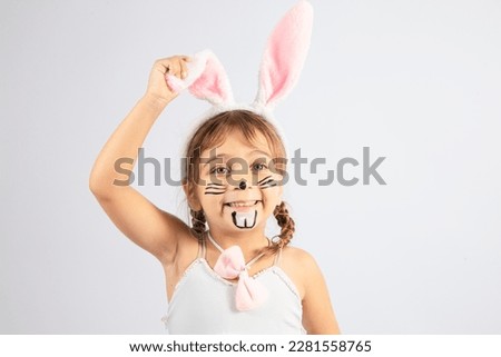 Cute little Caucasian girl with painted Easter bunny face wearing headbands