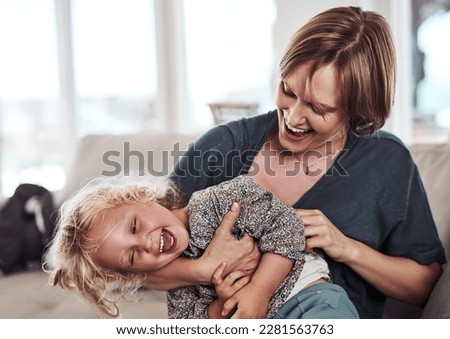 Ive got you now. an attractive young mother sitting and tickling her daughter during a day at home.