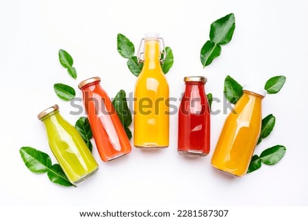 Citrus fruit juices, fresh and smoothies, food background, top view. Mix of different whole and cut fruits: orange, grapefruit, lime, tangerine with leaves and bottles with drinks on white table Royalty-Free Stock Photo #2281587307