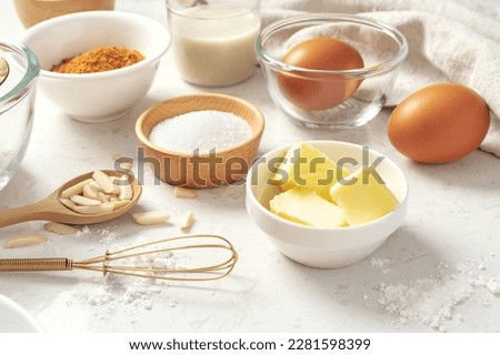 Baking pastry or cake ingredients, butter, sugar, flour, eggs and milk with whisk on marble table Royalty-Free Stock Photo #2281598399