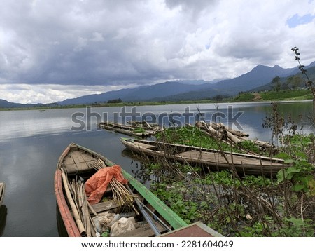 The view of the Selorejo dam with fishing boats looks beautiful surrounded by green hills and above the water there are water hyacinth plants in Ngantang Malang ,Selorejo