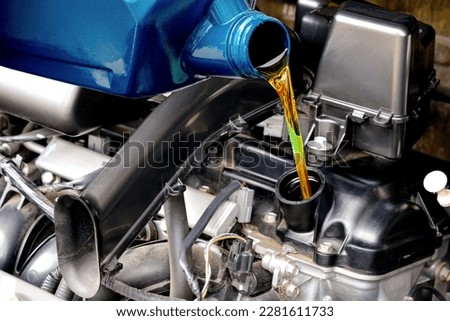 Refueling and pouring oil quality into the engine motor car Transmission and Maintenance Gear .Energy fuel concept. Royalty-Free Stock Photo #2281611733