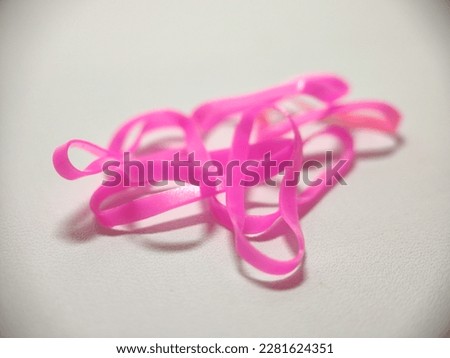 Collection of objects from a macro photo of pink mini rubber bands on a white background shot in close-up technique