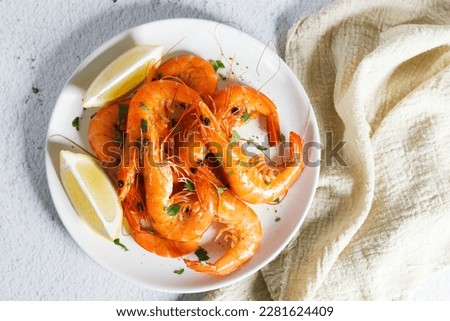Steamed shrimps with herbs and sliced lemon on white plate. Seafood dish. Royalty-Free Stock Photo #2281624409